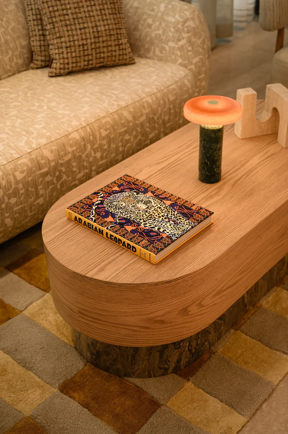 An 'Arabian Leopard' book and a glowing coral lamp on an oak coffee table.
